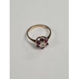 9ct gold cluster ring comprising central diamond chip surrounded round cut rubies, marked 375, size