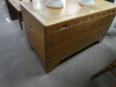 An oriental carved camphor wood blanket box and a similar coffee table with central drawer containin