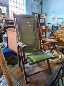 A n old mahogany Campaign style folding armchair with green leather upholstery