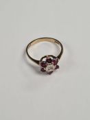 9ct gold cluster ring comprising central diamond chip surrounded round cut rubies, marked 375, size