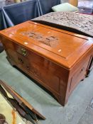 An Oriental camphor wood blanket box having carved front and lid