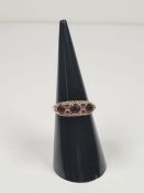 A 9ct gold half hooped ring, set with round cut garnets on decorative floral mount, marked 375 Birmi