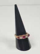 A 9ct gold half hooped ring set with 3 round cut rubies, separated with clear stones, on decorative