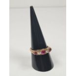 A 9ct gold half hooped ring set with 3 round cut rubies, separated with clear stones, on decorative