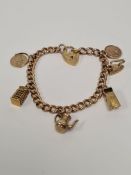 9ct yellow gold charm bracelet with heart shaped clasp, hung with 6 9ct gold charms to include St Ch