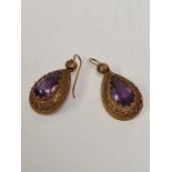 Pair of antique unmarked yellow metal drop earrings each set with a faceted pear shaped amethyst in