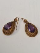 Pair of antique unmarked yellow metal drop earrings each set with a faceted pear shaped amethyst in