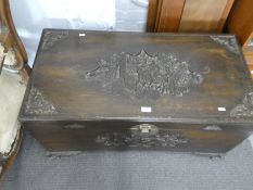 An Oriental carved camphor wood blanket box decorated figures horses and bats