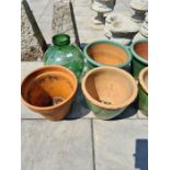 A green glass carboy and other garden pots