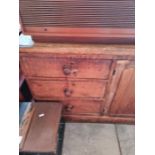 A Victorian pine dresser base having central cupboard with later rack back