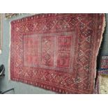 An old bokara style red ground rug having 3 central oblong panels with geometric border, 202 x 149cm