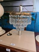 A three tier glass chandelier with pendant drops
