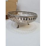 A decorative silver pierced fruit bowl having embossed flower rim and decorative body, on three feet