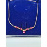 Cased 9ct yellow gold necklace with flat link chain hung with a decorative panel, inset rubies and d