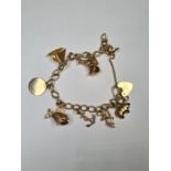 Modern 9ct yellow gold charm bracelet hung with nine 9ct gold charms including Pig, Sailing Boat, Fi