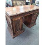 A late 19th century continental carved walnut pedestal desk having cupboard and drawers