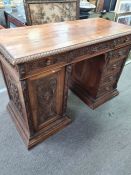A late 19th century continental carved walnut pedestal desk having cupboard and drawers