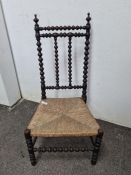 A 19th century bobbin chair with rush leaf