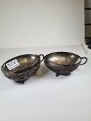 A pair of white metal lined coconut shells, with one handle and on three feet. Very decoratively car
