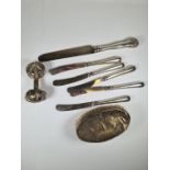 A quantity of silver handled knives, a silver backed brush and a white metal rattle AF, and another