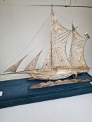 A cased white metal boat having a seated figure sailing. Very ornate and decorative pierced details,