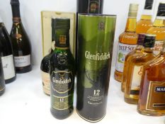 A bottle of Glenfiddich Single Malt Whiskey, a similar smaller bottle and a vintage bottle of Courvo