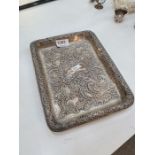 A heavily embossed Edwardian silver tray having scrolls, foliate and floreated details standing in r