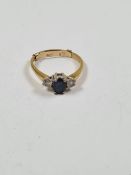 18K yellow gold three stone ring with central oval blue sapphire flanked with two brilliant cut diam
