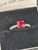 19ct white gold ring with central round cut Burmese ruby in 4 claws supports, the band inset with di