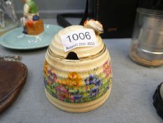 A Clarice Cliff honey pot having floral decoration with butterfly to lid