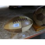 A wooden decorative football and a similar Rugby ball