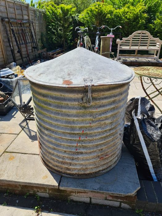 An old galvanised circular storage bin having pointed lid