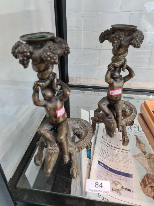 A pair of reproduction brass candlesticks of cherubs riding crocodiles