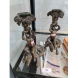 A pair of reproduction brass candlesticks of cherubs riding crocodiles