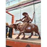 A large wooden carving of Man riding Water Buffalo, other carvings and a modern oval mirror