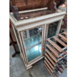 A white painted and gilt decorated two door display cabinet