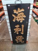 An oriental wooden oblong plaque having carved gilt lettering / words. 45.5cm x 121.5cm