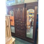 A late Victorian carved walnut wardrobe having central drawers and cupboard