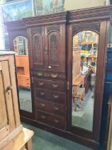 A late Victorian carved walnut wardrobe having central drawers and cupboard