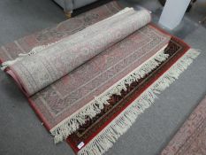 A modern Caucasian style rug having 4 central motifs and one other pink floral rug
