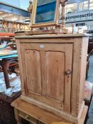 An old pine cupboard having one door on modern pine side table and two other items