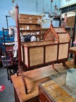 An antique style repro mahogany cradle having cane decoration on splay legs