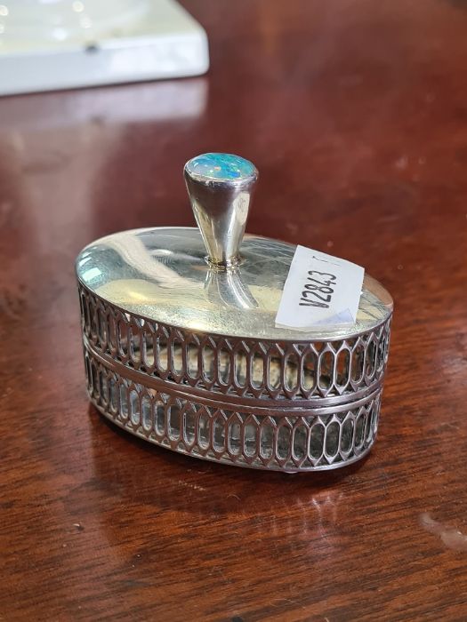 A white metal oval cricket holder having pierced sides