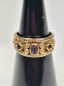 Decorative 9ct yellow gold band ring with decorative panel set amethyst, AF, one missing, marked 375