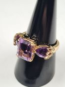 Contemporary 10K yellow gold dress rings with central cushion cut amethyst flanked with two pear sha