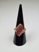 Yellow gold dress ring with central panel set with round cut rubies, and each shoulder set round cut