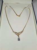 Cased 9ct gold snake design chain leading to a fixed crossover style panel hung with a sapphire and