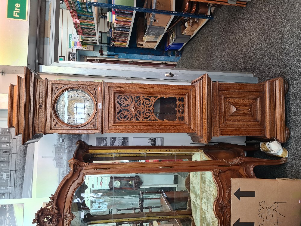 A 1920s oak longcase clock having round dial, 8 day, the glazed door having fretwork decoration, 220