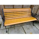 A garden bench with decorative metal ends, refurbished and painted black, with new wood and protecte