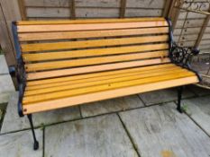 A garden bench with decorative metal ends, refurbished and painted black, with new wood and protecte